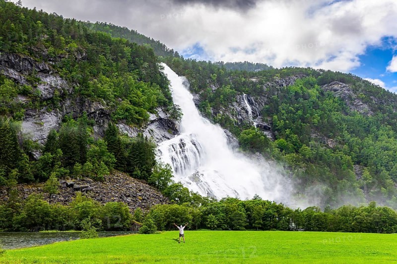 Incredible waterfalls in Norway. Huge powerful waterfal Vidfossen. White water foam envelops the foot of the waterfall. Lush clouds and constant cold rain