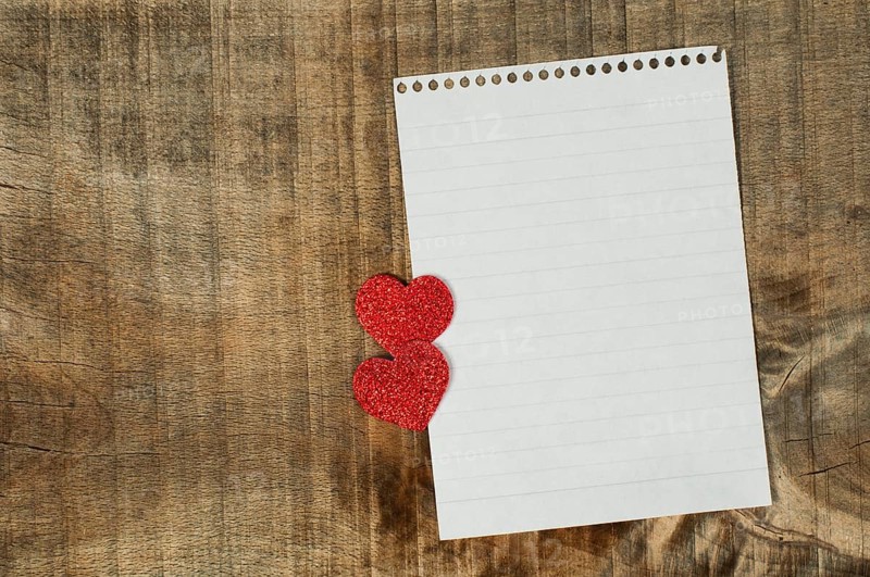 Red hearts and white paper sheet on wooden background