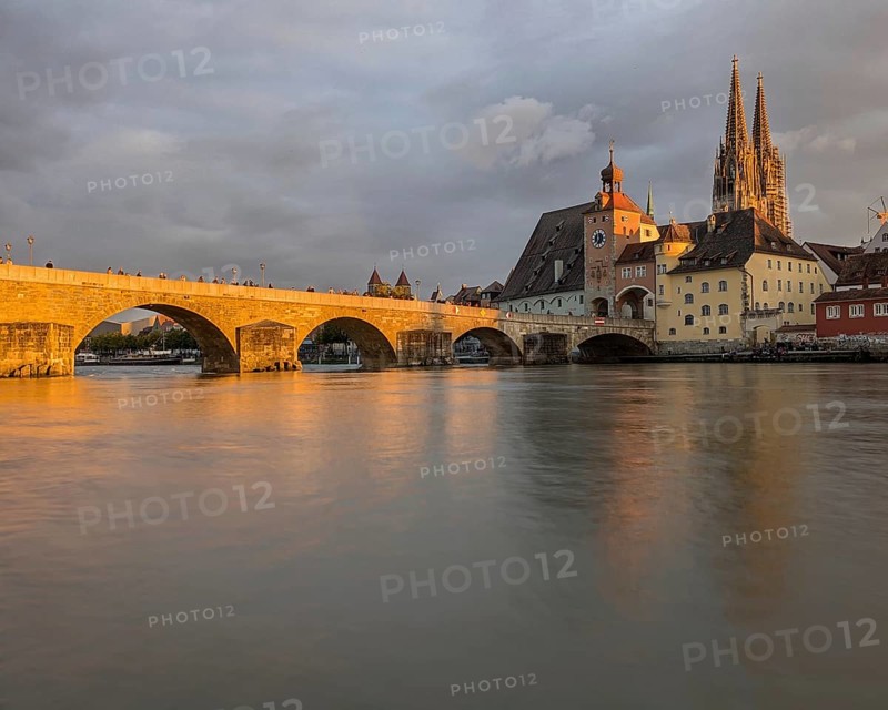 Serene riverside scene at sunset with a bridge, cathedral, and historic town reflecting on the water, A stone bridge and cathedral at sunset reflecting in a calm river. Regensburg, Germany, Europe