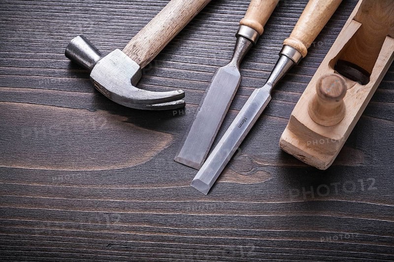 Claw hammer shaving plane and flat chisels on vintage wooden board construction concept