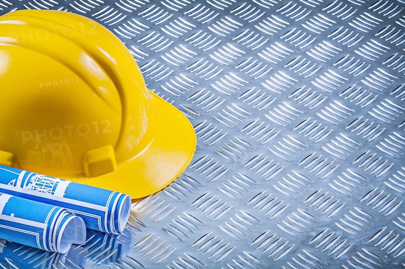 Blue engineering drawings building helmet on corrugated metal background construction concept