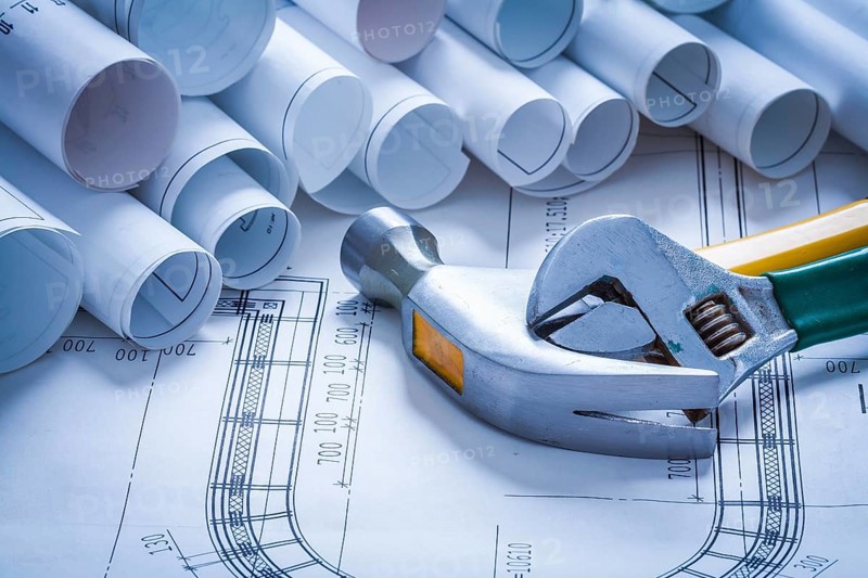 Claw hammer adjustable spanner and pile of blueprint rolls construction concept