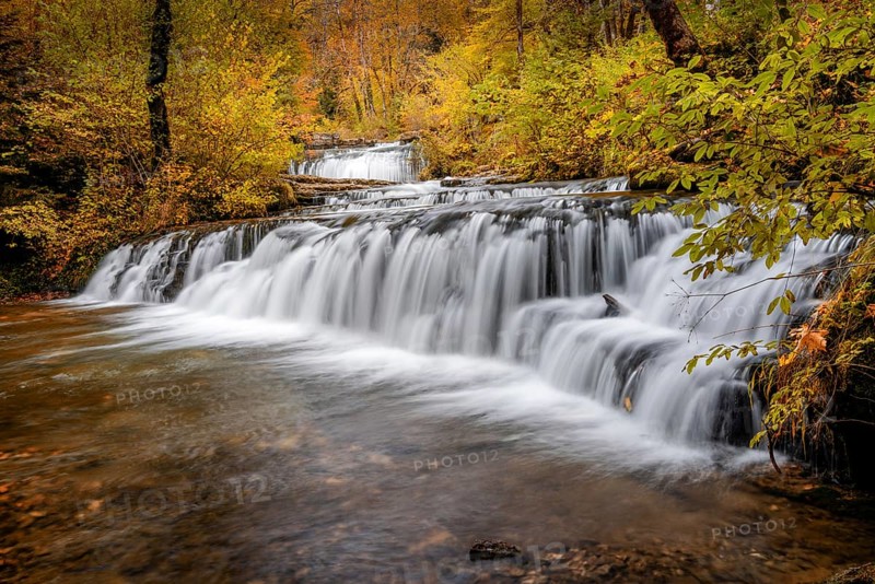 A beautiful autumn forest landscape with idyllic waterfall and pool