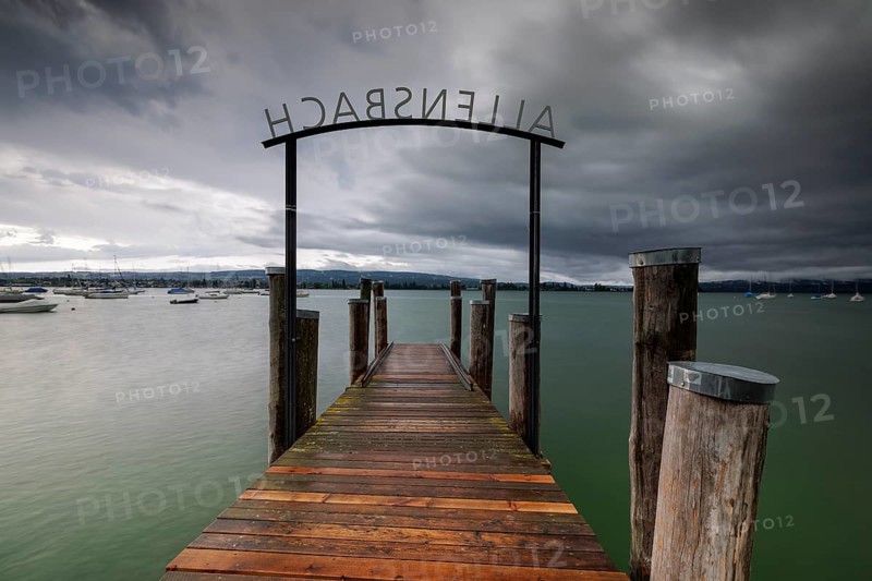 Wooden footbridge leads into a lake under a stormy sky, Allensbach, Untersee, Lake Constance, Constance District, Baden-Württemberg, Germany, Europe