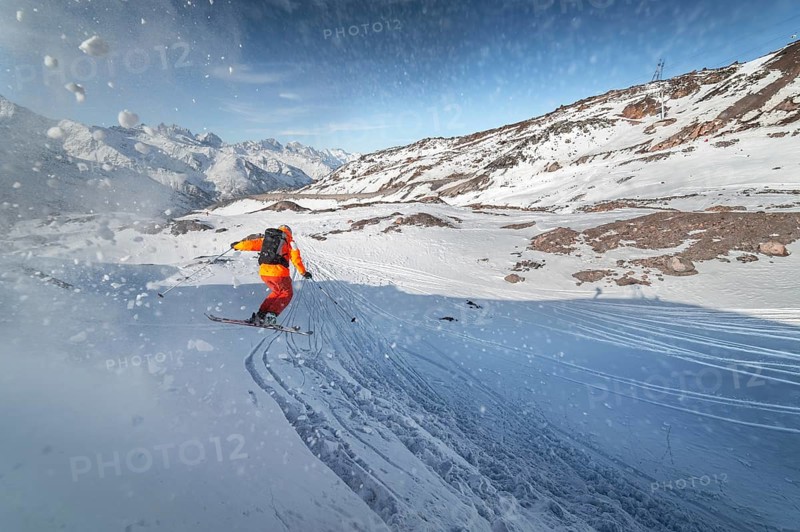 Skier rides on a snowy slope on a sunny day at sunset against the backdrop of the mountains. The concept of winter skiing