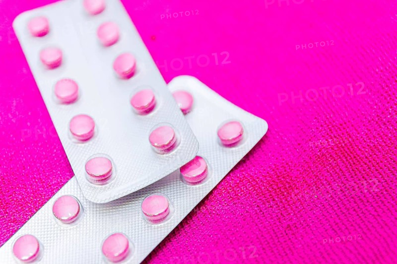 Pink pills in a blister on a pink background