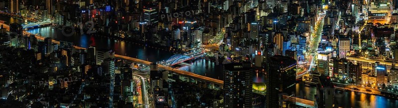 A paorama picture of the Sumida River and nearby cityscape, as seen from above, at night
