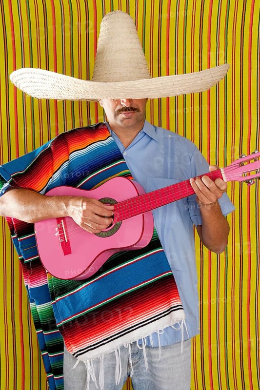 Mexican man with poncho and sombrero playing guitar typical of Mexico