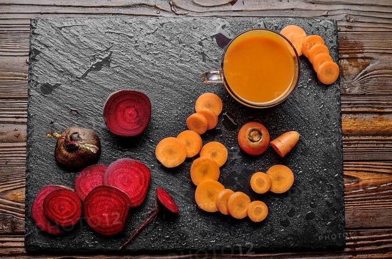Top view at vegetable background of beets carrots and juice on kitchen table close up view