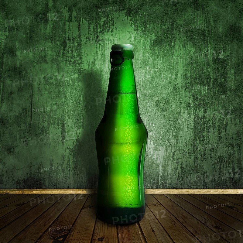 Cool beer bottle at wooden floor over grunge wall