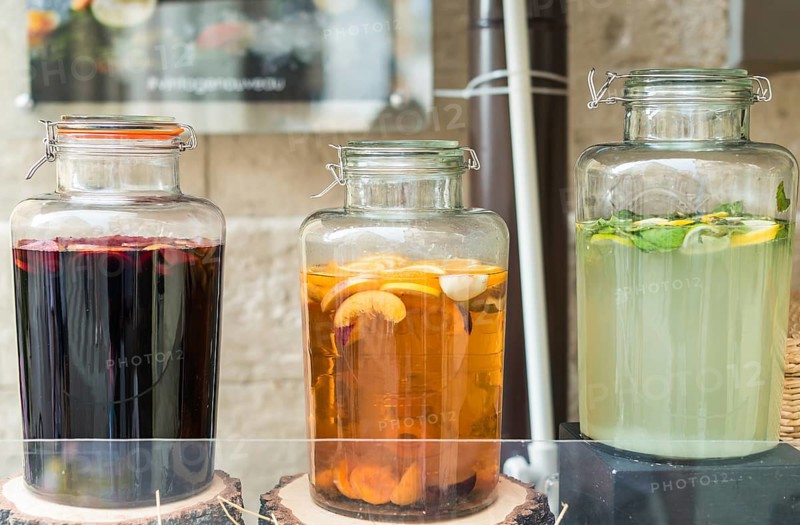 Glass jars filled with lemon, orange and apple juice on wooden stumps