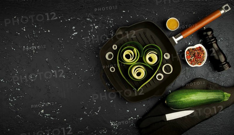 Fresh green zucchini in a pan on a dark table. The view from the top. Copy space