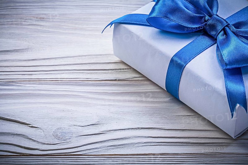 Present box with blue satin tape on wooden board celebrations concept