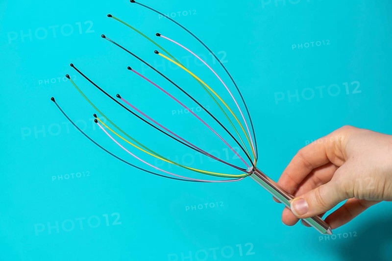 Scalp massager for home. Close up of scalp massaging brush for hair growing routine. Anti stress acupuncture metal octopus tool equipment. Manual device for home Medicine and cosmetology. SPA treatment