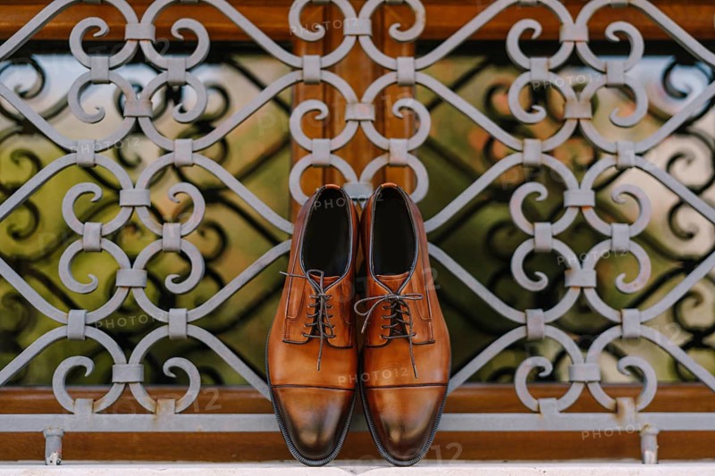 Stylish brown men's shoes made of genuine leather by the window with a metal lattice.