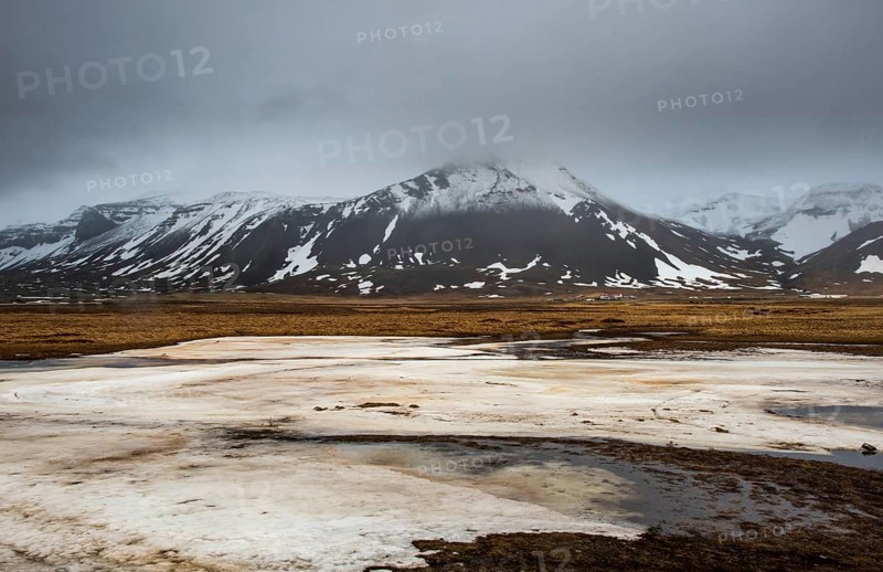 Icelandic landscape with frozen lake, mountains and meadow land covered in snow at snaefellsnes peninsula in Iceland