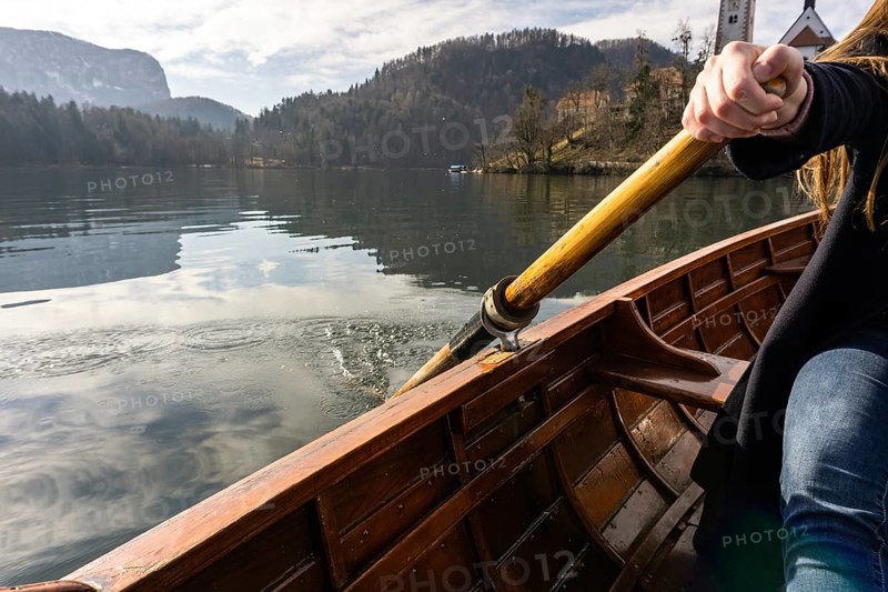 Young woman using paddle on a wooden boat, Lake Bled Slovenia rowing on wooden boats on a sunny day