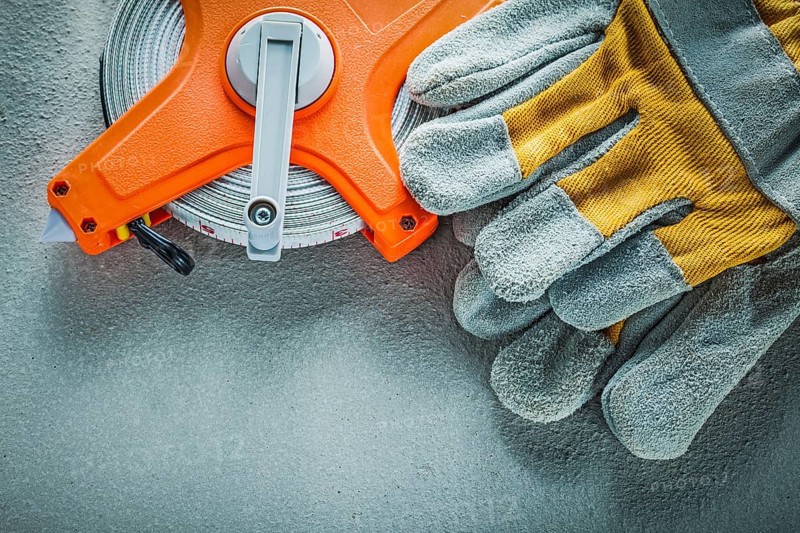 Safety gloves measuring tape on concrete background