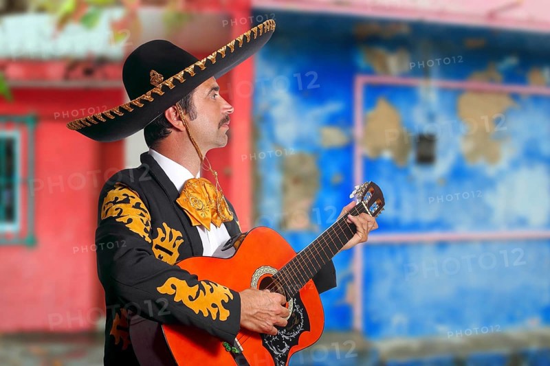 Charro Mariachi singer playing guitar in Mexico houses background