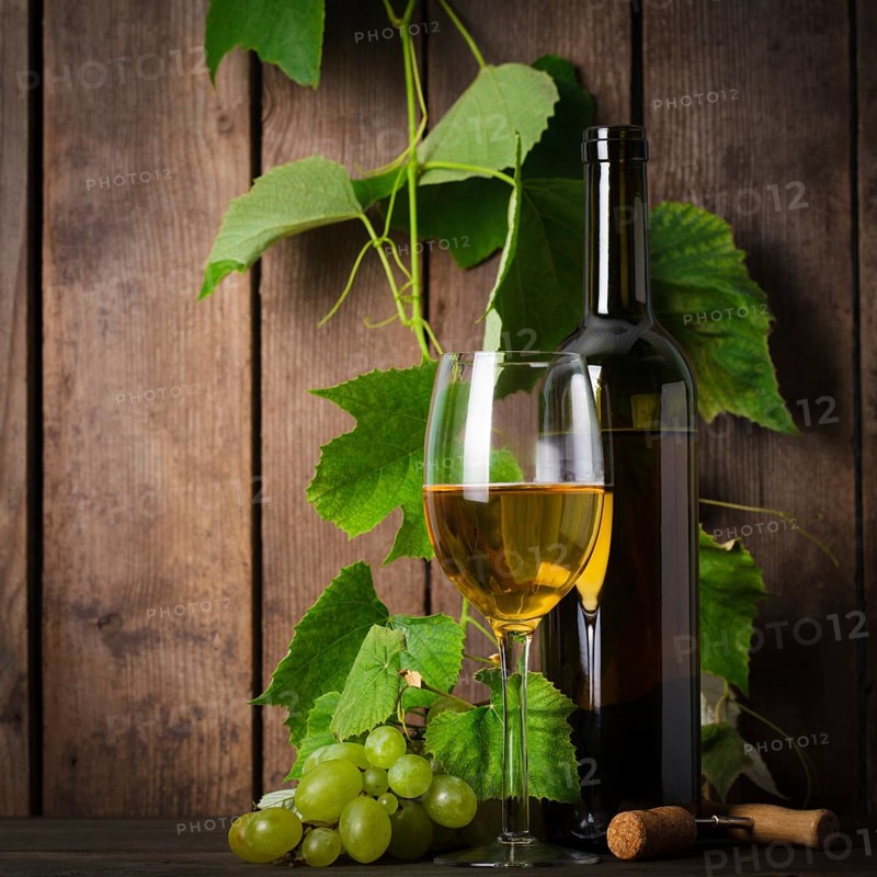 White wine, grapes, corkscrew, and bottle on wood background closeup