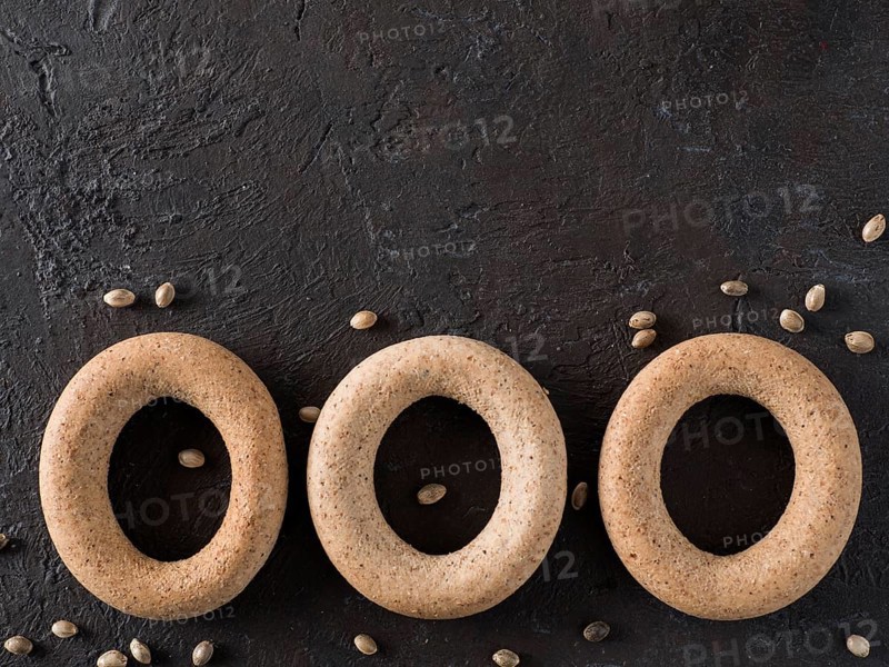 Ring-shaped cracknel with whole grain hemp seed flour and hemp seeds on black background. ring-shaped cracknel close up. Copy space Top view or flat lay