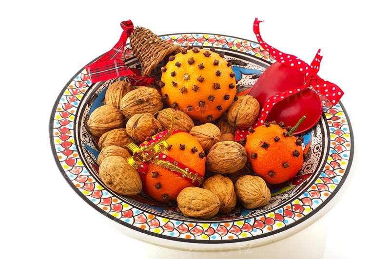 Orange with cloves and walnuts on bowl isolated over white