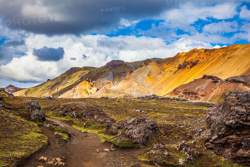 Travel to Iceland in July, volcanic summer tundra. Multi-colored rhyolite mountains - orange, yellow, green and blue