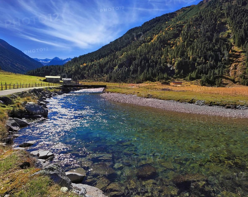 Austrian Alps. Starting famous Krimml waterfalls. Crystal clear water sparkles in the midday sun. Through the narrow creek wooden bridge spanned