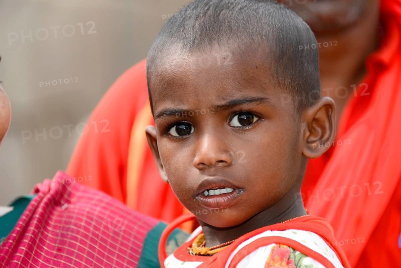 Coastal temple of Mahabalipuram, Mamallapuram, A child in red clothes with a curious and serious expression on his face, Mahabalipuram, Tamil Nadu, South India, India, Asia