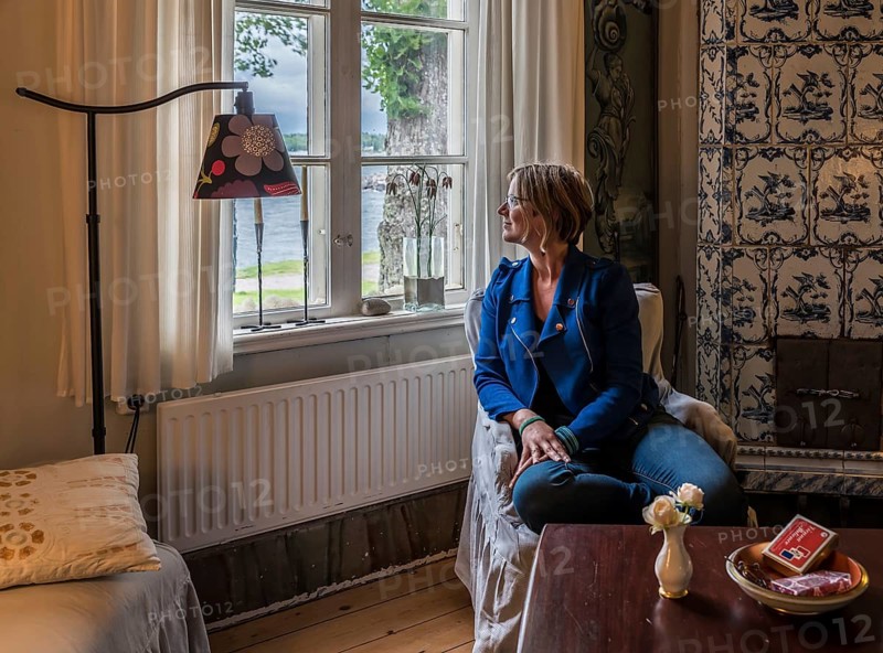 Oregrund, Uppland, Sweden, 30 07 2019 Woman posing in the traditional 19th century wooden interior design of a bed and breakfast living room, Europe