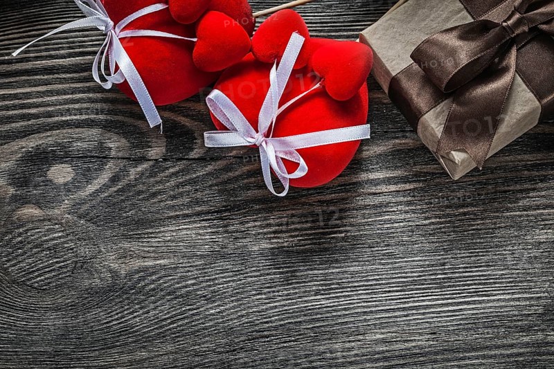 Present box red hearts on vintage wooden board holidays concept