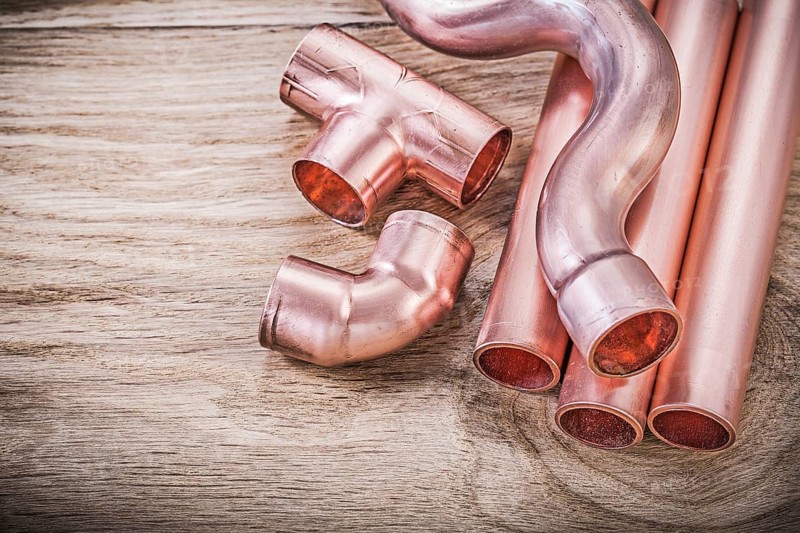 Copper water pipe coupling tools on wooden board plumbing brassware concept