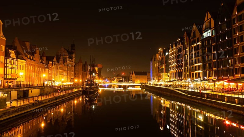 Old town in Gdansk at night. The riverside on Granary Island reflection in Moltawa River Cityscape at twilight. Ancient crane at dusk. Visit Gdansk Poland Travel destination. Tourist attraction