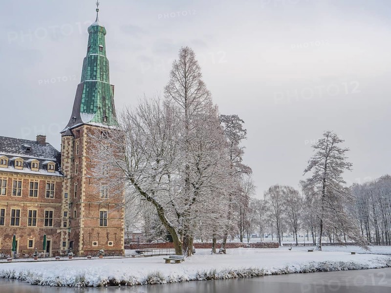 Castle in winter, surrounded by snow-covered trees, with a frozen lake in the foreground, Raesfeld, münsterland, germany