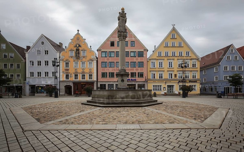 An empty market square with a statue surrounded by pastel-coloured historic buildings, Old Town Mindelheim, Bavaria, Germany, Europe