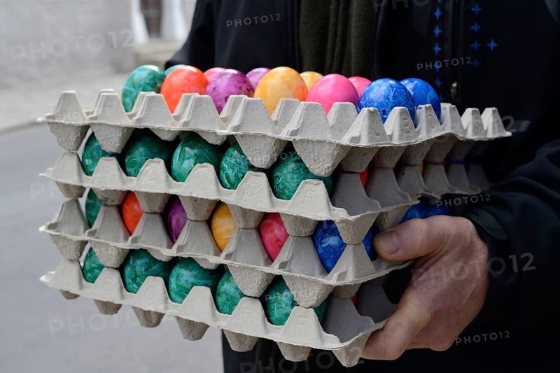 Person holding several stacks of coloured eggs for Easter