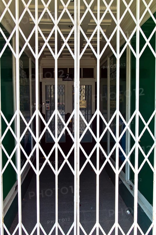 A shop is closed by a scissor gate. Symbol photo for shop opening hours