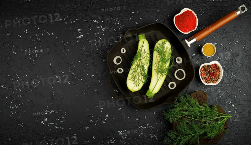 Fresh green zucchini in a pan on a dark table. The view from the top. Copy space