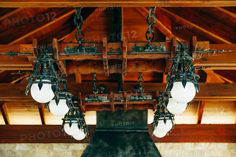 A huge wrought iron chandelier with round white balls. Metal pendant chandelier in the knight's style.