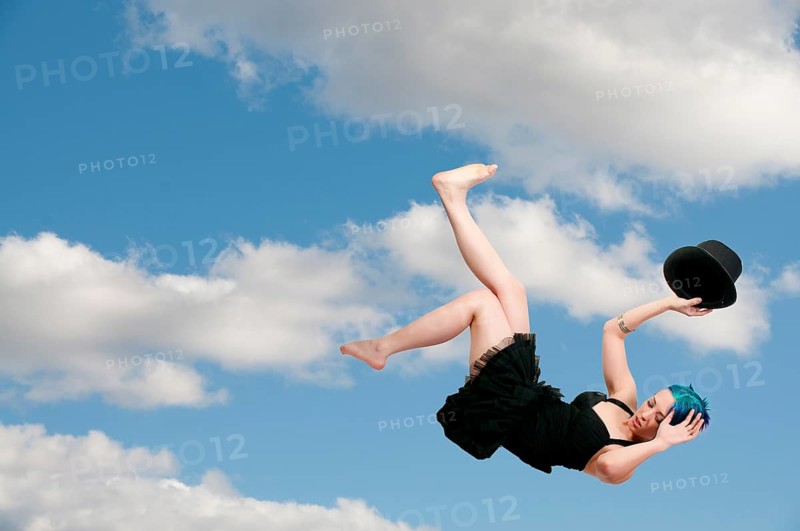 A beautiful young actress dancer wearing a top hat flying through the sky or falling through the air