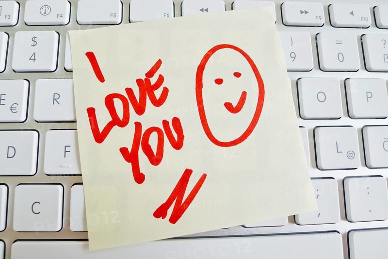 A note lies on the keyboard of a computer as a reminder: I love you Austria