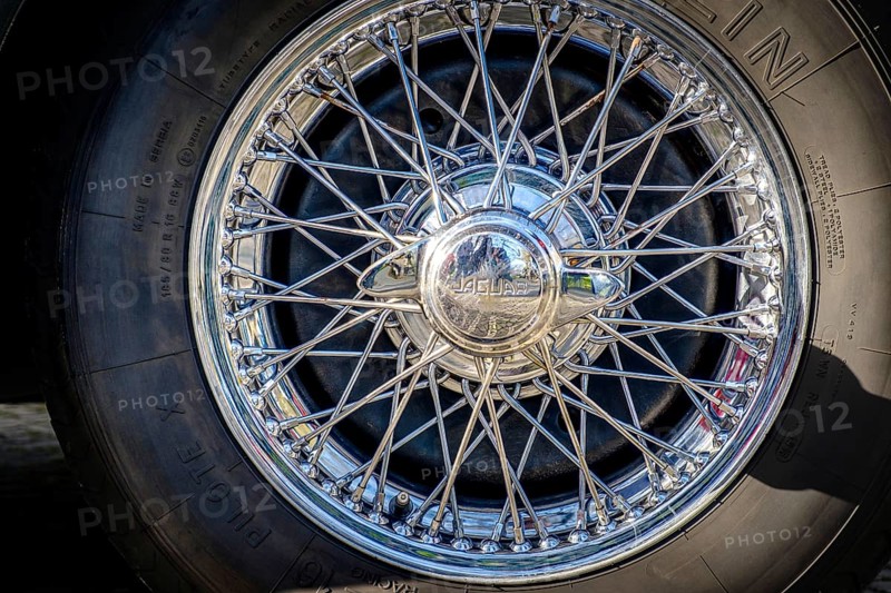 Lisbon, Portugal, Jan 20, 2024: Car design detail of Jaguar chrome wire wheel, stainless steel spokes, polished and chrome-plated with signs of wear-and-tear and bespoke 2-eared wire wheel spinner for splined hub with Jaguar logo. Michelin tyre, Europe