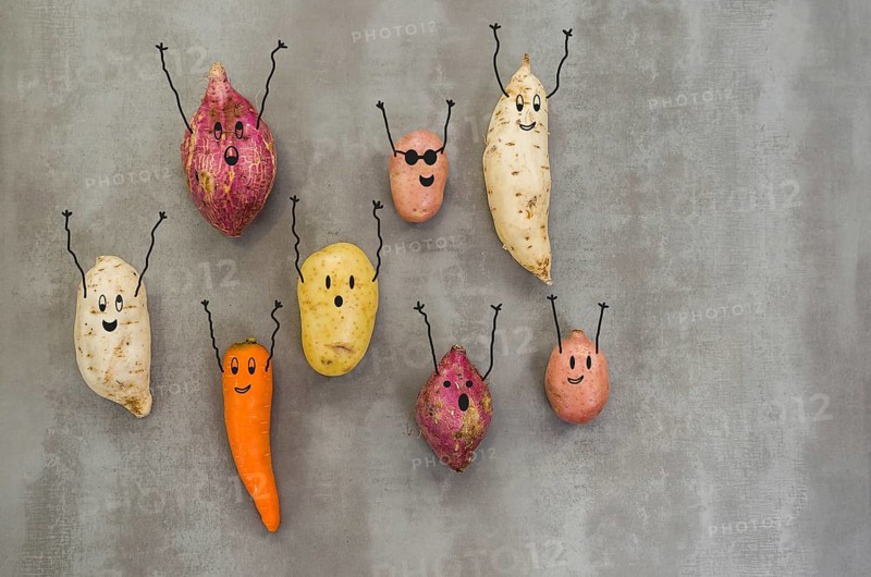 Great concept of healthy eating, vegetables with happy faces with arms up, potato, sweet potato, carrot. Gray background, polished concrete