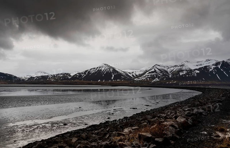 Icelandic dramatic landscape with frozen lake and mountains covered in snow in Iceland
