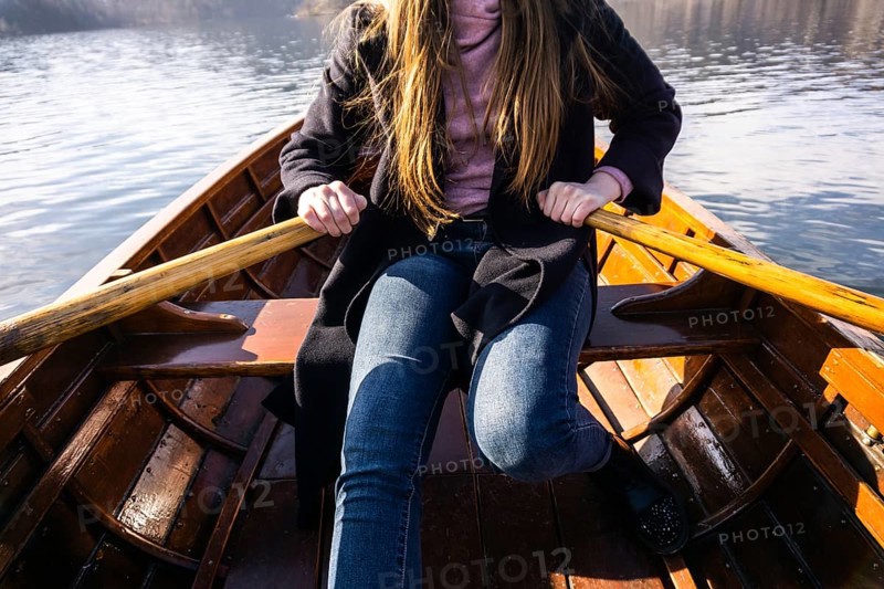 Young woman using paddle on a wooden boat, Lake Bled Slovenia rowing on wooden boats on a sunny day