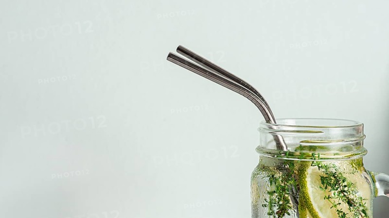 Cold drink in mason jar with metal straw on white background. Lemonade or detox water with lime and thyme in glass jar with copy space for text or design. Recyclable straws, zero waste concept. Banner