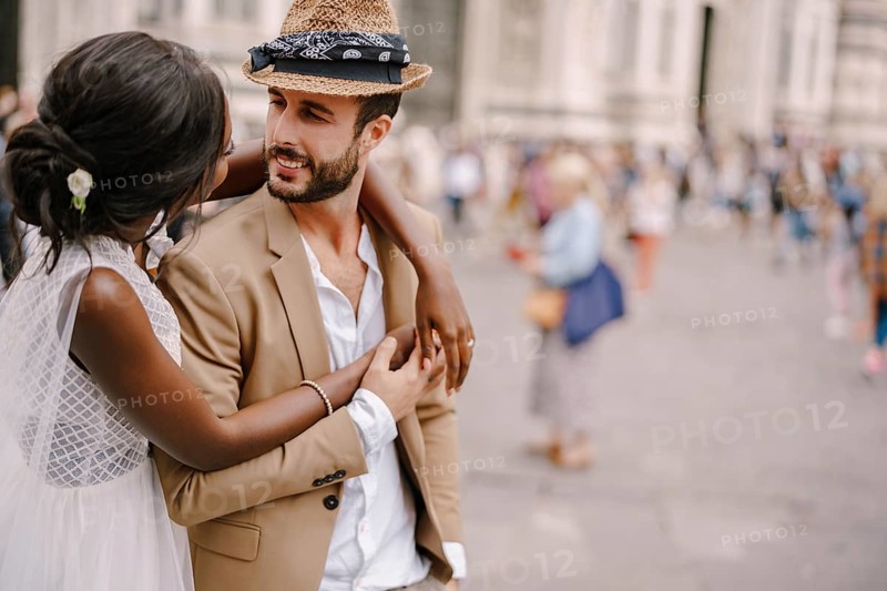 African-American bride hugs from behind a Caucasian groom. Interracial wedding couple. Wedding in Florence, Italy, Europe