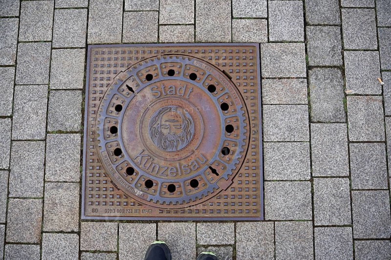 Manhole cover with motif on John the Baptist, Bible, town coat of arms, coat of arms, Künzelsau, Kocher valley, Kocher, Hohenlohe, Germany, Europe