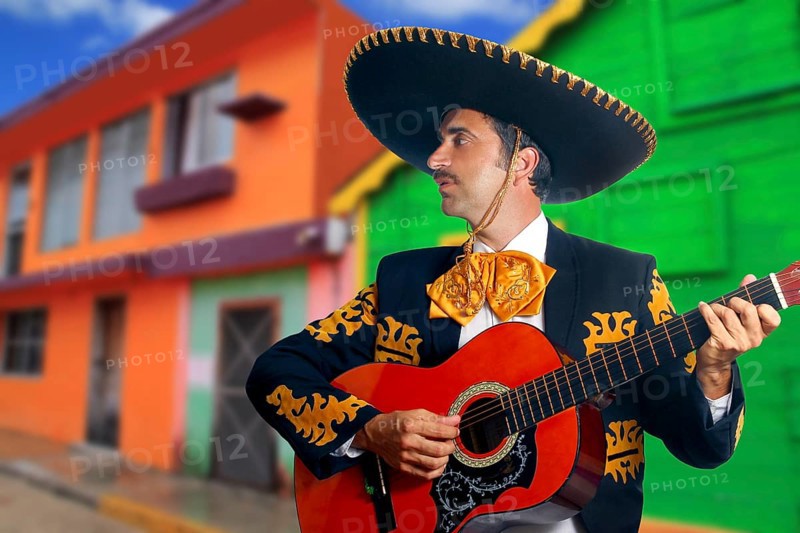 Charro Mariachi singer playing guitar in Mexico houses background