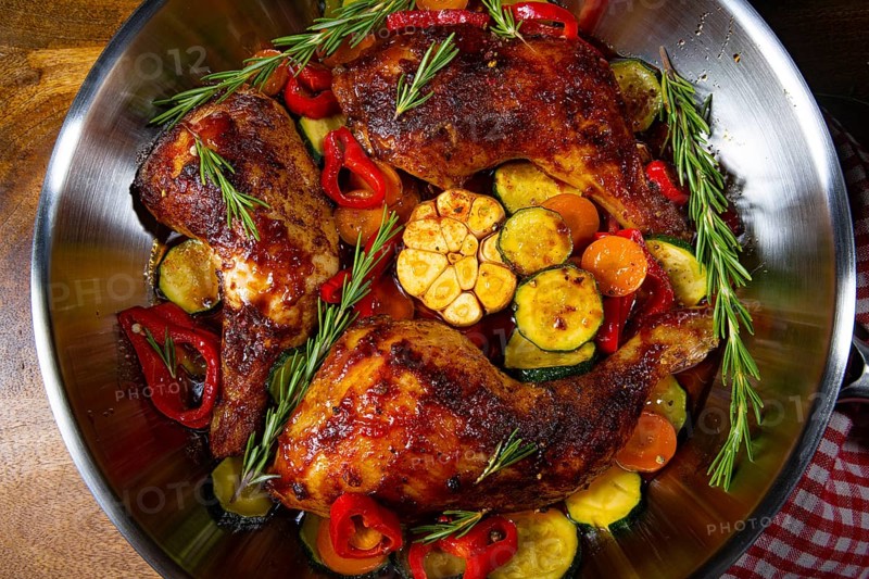 Roasted chicken legs with various vegetables and spices